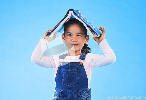 Image of School, head and portrait of child with book for knowledge or learning isolated in a studio blue background. Clever, smart and young girl kid with notebook happy for education, story or reading