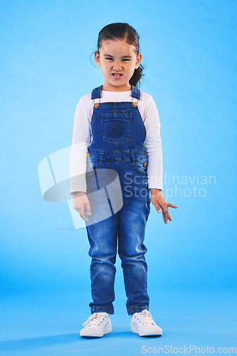 Image of Angry, attitude and portrait of child on blue background with upset, mad and frustrated facial expression. Behaviour, youth and young girl with body language for anger, tantrum and emotion in studio