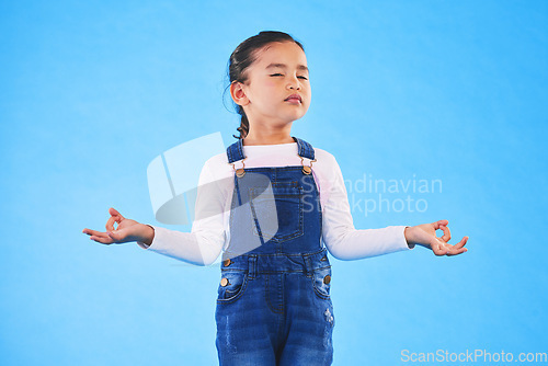 Image of Girl child, zen and meditation in studio with eyes closed, peace and wellness by blue background. Female kid, mindfulness and balance chakra for health, breathing and development with yoga for energy