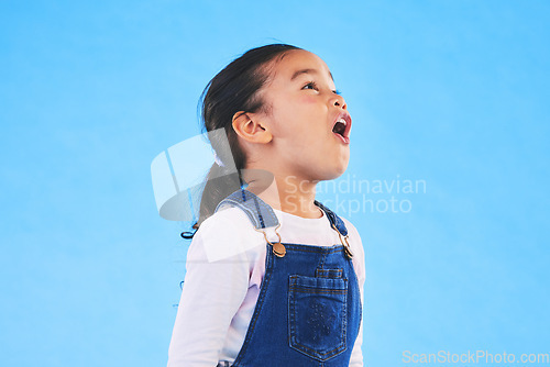 Image of Shock, wow and girl child in a studio with mockup space for advertising, promotion or marketing. Youth, wtf and young kid model with omg and surprise face expression by blue background with mock up.