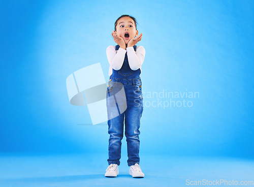 Image of Shocked, wow and girl surprise with hands to face in studio with fear and scared from danger. Alarm, blue background and young child from Hawaii with scary, omg and emoji face of a kid in danger
