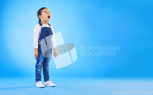 Image of Shock, surprise and girl child in a studio with mockup space for advertising, promotion or marketing. Wow, wtf and full length of a kid model with omg face expression by blue background with mock up.