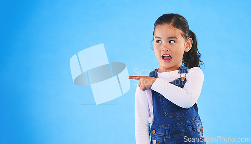 Image of Pointing, blue background and girl with mockup space for sale, advertising and promotion. Emoji, happy and young child in studio with hand gesture for discount information, announcement and news