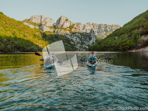 Image of A group of friends enjoying having fun and kayaking while exploring the calm river, surrounding forest and large natural river canyons