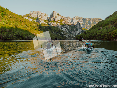 Image of A group of friends enjoying having fun and kayaking while exploring the calm river, surrounding forest and large natural river canyons