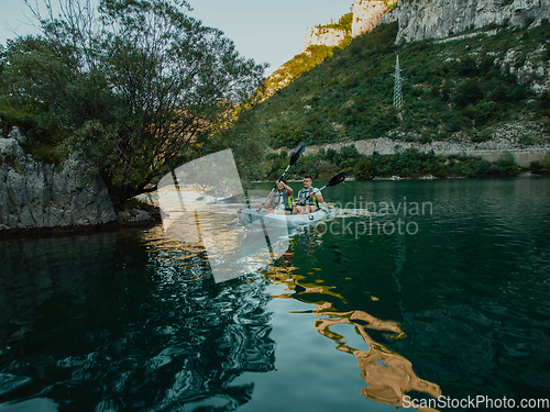 Image of A group of friends enjoying having fun and kayaking while exploring the calm river, surrounding forest and large natural river canyons