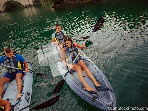 Image of A group of friends enjoying having fun and kayaking while exploring the calm river, surrounding forest and large natural river canyons