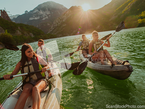 Image of A group of friends enjoying fun and kayaking exploring the calm river, surrounding forest and large natural river canyons during an idyllic sunset.