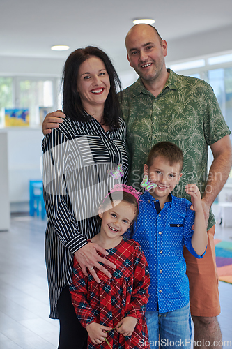 Image of Portrait of a happy family. Photo of parents with children in a modern preschool classroom. Selective focus