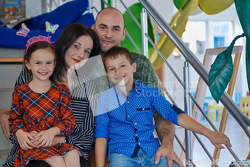 Image of Portrait of a happy family. Photo of parents with children in a modern preschool classroom. Selective focus