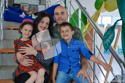 Image of Portrait of a happy family. Photo of parents with children in a modern preschool classroom. Selective focus