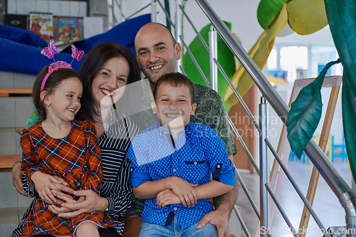 Image of Portrait of a happy family. Photo of parents with children in a modern preschool classroom. Selective focus