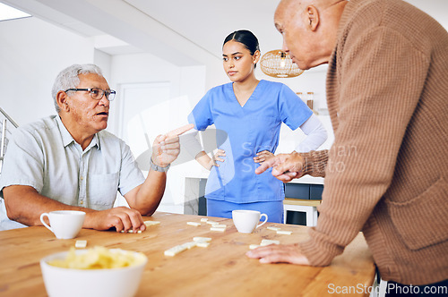 Image of Nurse, senior and fighting over a game of dominoes with people in a retirement home for assisted living. Healthcare, medical and a female medicine professional looking at upset old men arguing