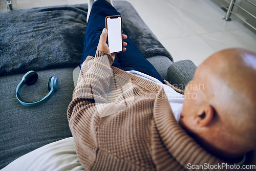 Image of Phone screen, mockup and a man on a home sofa for internet advertising with social media or a website. Behind a person with a smartphone and blank space for network, streaming music and headphones