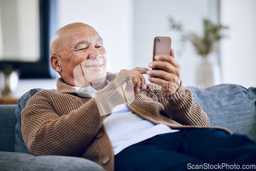 Image of Smile, typing and a senior man with a phone on the sofa for social media, contact or commmunication. Happy, relax and an elderly person on the home couch with a mobile for an app or reading a chat