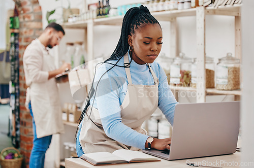 Image of Grocery store, small business and black woman at counter with laptop for stock inventory, planning and sales report. Computer, internet and manager at sustainable supermarket with eco friendly care.