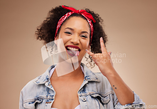 Image of Woman, horns sign and studio portrait with tongue, comic smile and funny face with beauty by brown background. African girl, model or student with icon, crazy and rock star hand with laugh for beauty