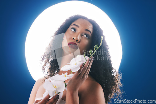 Image of Beauty, circle light and woman with flowers for wellness, natural cosmetics and skincare in studio. Spa, neon aesthetic and person with orchid for makeup, face glamour and facial on blue background