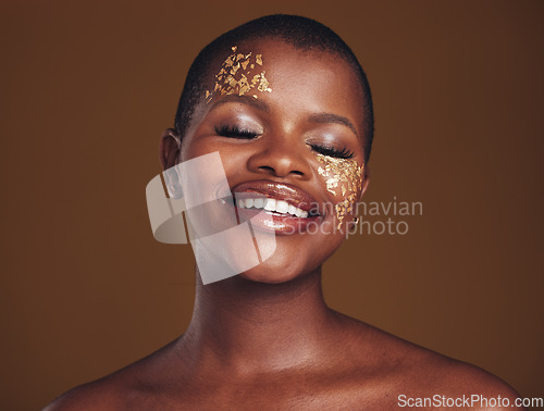 Image of Gold, glitter and black woman smile from beauty with makeup and studio with sparkle cosmetics. Brown background, relax and female model with golden paint for skin glow and creative facial shine