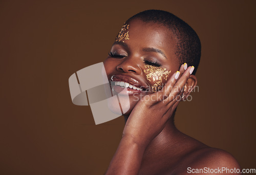 Image of Gold, makeup and woman with a smile from luxury treatment and facial spa mask. Glitter art, creative dermatology and African female person from skincare and cosmetics in studio with brown background