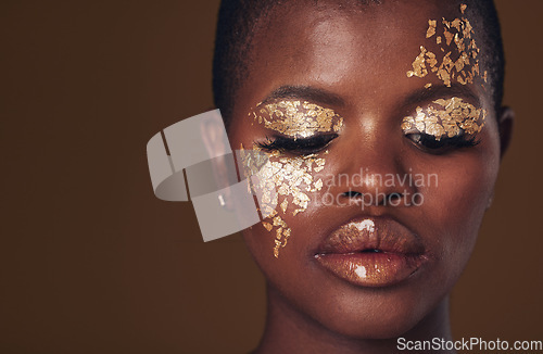 Image of Gold, face and black woman with makeup for beauty aesthetics isolated in a studio brown background eyes closed. Creative, luxury and African person with cosmetic glamour, art or design for skincare