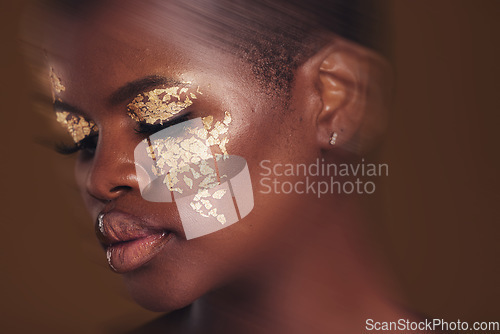 Image of Gold beauty, blur and black woman with makeup and face closeup with cosmetics in studio. Brown background, African female model and glitter with golden shine and glow from facial paint sparkle