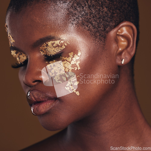 Image of Gold, art and face of black woman with makeup for beauty aesthetics isolated in a studio brown background eyes closed. Creative, luxury and African person with cosmetic glamour or design for skincare