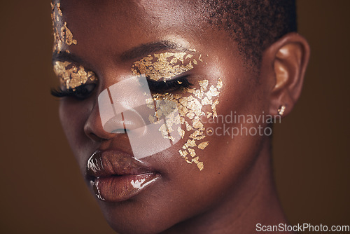 Image of Gold, creative and black woman with makeup for beauty aesthetics isolated in a studio brown background eyes closed. Art, luxury and face of African person with cosmetic glamour or design for skincare