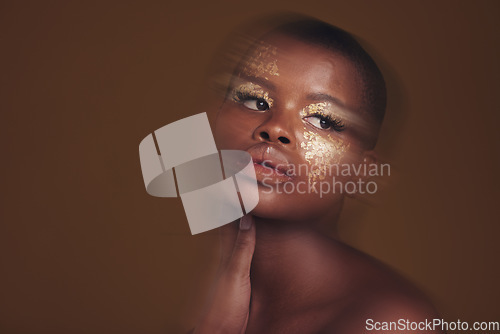 Image of Gold beauty, blurred and black woman makeup with mockup space and cosmetics in studio. Brown background, African female model and glitter with golden shine and skin glow from facial paint sparkle