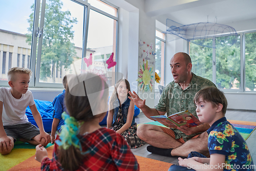 Image of Reading time in an elementary school or kindergarten, a teacher reading a book to children in an elementary school or kindergarten. The concept of pre-school education. Selective focus