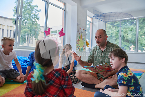 Image of Reading time in an elementary school or kindergarten, a teacher reading a book to children in an elementary school or kindergarten. The concept of pre-school education. Selective focus