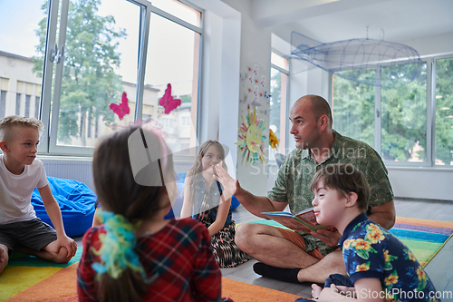 Image of Reading time in an elementary school or kindergarten, a teacher reading a book to children in an elementary school or kindergarten. The concept of pre-school education. Selective focus