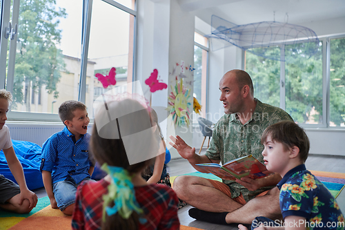 Image of Reading time in an elementary school or kindergarten, a teacher reading a book to children in an elementary school or kindergarten. The concept of pre-school education. Selective focus