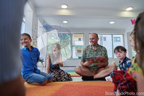 Image of Reading time in an elementary school or kindergarten, a teacher reading a book to children in an elementary school or kindergarten. The concept of pre-school education. Selective focus