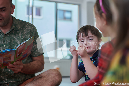 Image of Reading time in an elementary school or kindergarten, a teacher reading a book to children in an elementary school or kindergarten. The concept of pre-school education. Selective focus