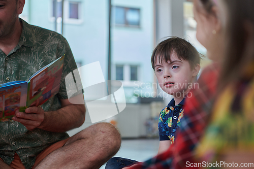 Image of Reading time in an elementary school or kindergarten, a teacher reading a book to children in an elementary school or kindergarten. The concept of pre-school education. Selective focus