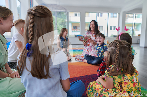 Image of Reading time in an elementary school or kindergarten, a teacher reading a book to children in an elementary school or kindergarten. The concept of pre-school education. Selective focus