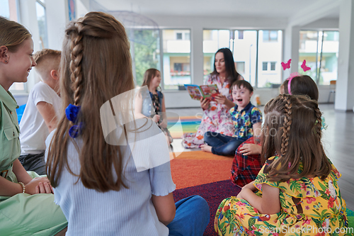 Image of Reading time in an elementary school or kindergarten, a teacher reading a book to children in an elementary school or kindergarten. The concept of pre-school education. Selective focus