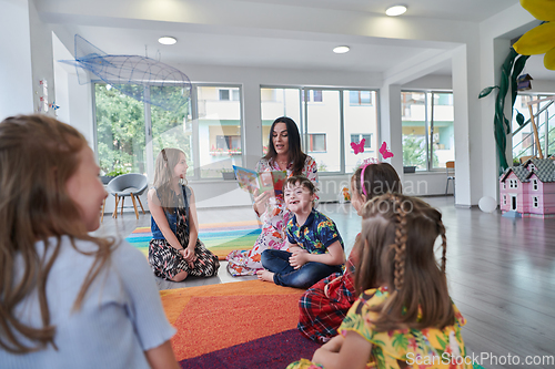 Image of Reading time in an elementary school or kindergarten, a teacher reading a book to children in an elementary school or kindergarten. The concept of pre-school education. Selective focus