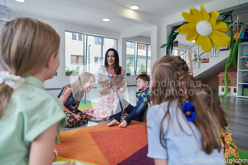 Image of Reading time in an elementary school or kindergarten, a teacher reading a book to children in an elementary school or kindergarten. The concept of pre-school education. Selective focus