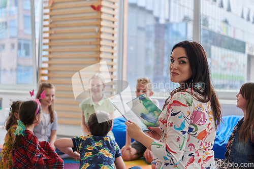 Image of Reading time in an elementary school or kindergarten, a teacher reading a book to children in an elementary school or kindergarten. The concept of pre-school education. Selective focus