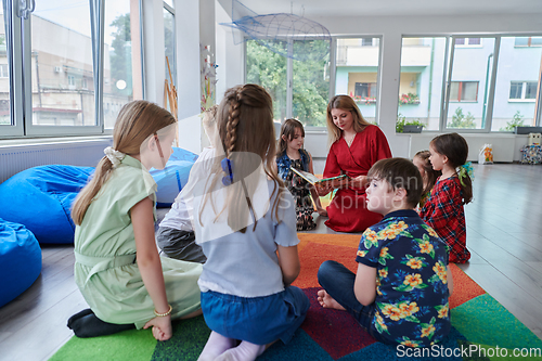 Image of Reading time in an elementary school or kindergarten, a teacher reading a book to children in an elementary school or kindergarten. The concept of pre-school education. Selective focus