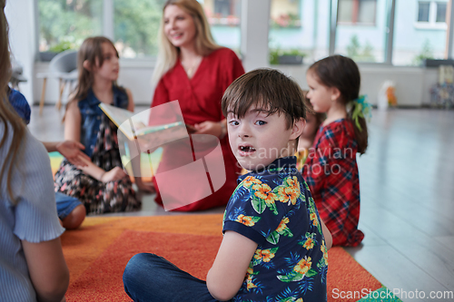 Image of Reading time in an elementary school or kindergarten, a teacher reading a book to children in an elementary school or kindergarten. The concept of pre-school education. Selective focus