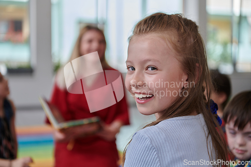 Image of Reading time in an elementary school or kindergarten, a teacher reading a book to children in an elementary school or kindergarten. The concept of pre-school education. Selective focus