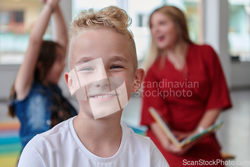 Image of Reading time in an elementary school or kindergarten, a teacher reading a book to children in an elementary school or kindergarten. The concept of pre-school education. Selective focus