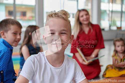 Image of Reading time in an elementary school or kindergarten, a teacher reading a book to children in an elementary school or kindergarten. The concept of pre-school education. Selective focus