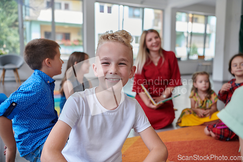 Image of Reading time in an elementary school or kindergarten, a teacher reading a book to children in an elementary school or kindergarten. The concept of pre-school education. Selective focus