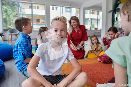 Image of Reading time in an elementary school or kindergarten, a teacher reading a book to children in an elementary school or kindergarten. The concept of pre-school education. Selective focus