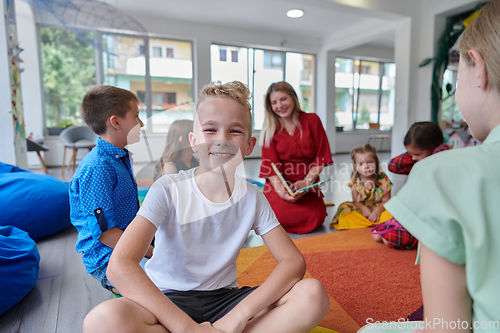 Image of Reading time in an elementary school or kindergarten, a teacher reading a book to children in an elementary school or kindergarten. The concept of pre-school education. Selective focus