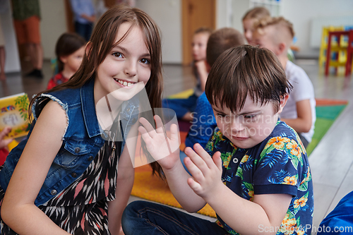 Image of A girl and a boy with Down's syndrome in each other's arms spend time together in a preschool institution